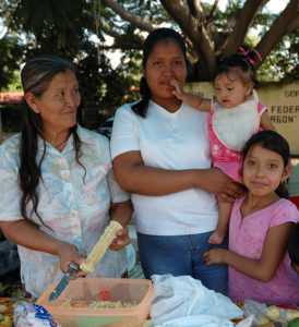 Mexican family prepares corn for a community event.